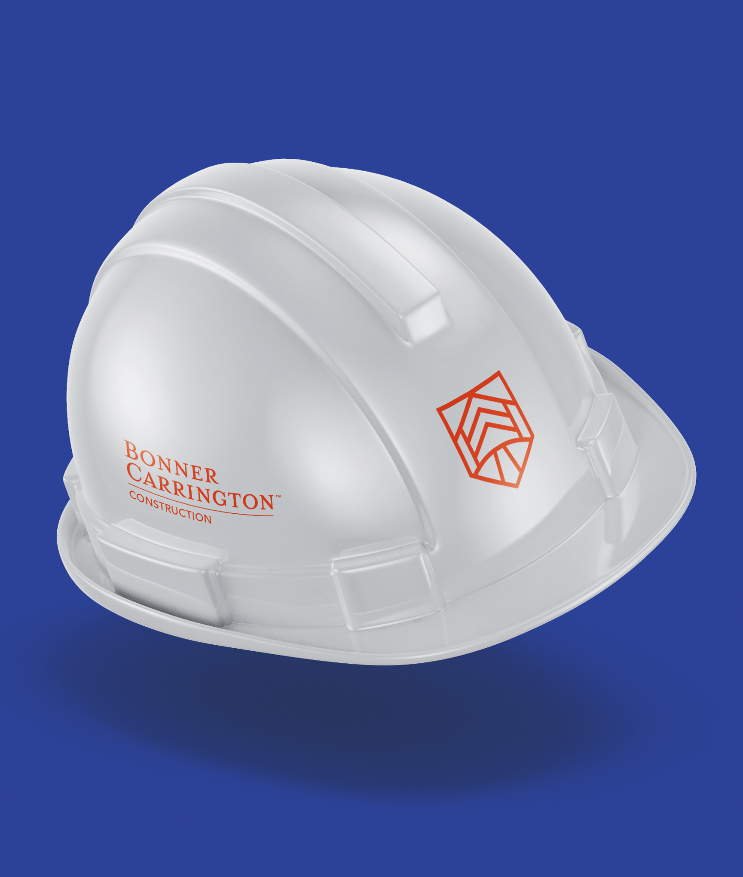 A white construction hard hat featuring the Bonner Carrington logo and an orange geometric symbol, placed against a solid blue background.
